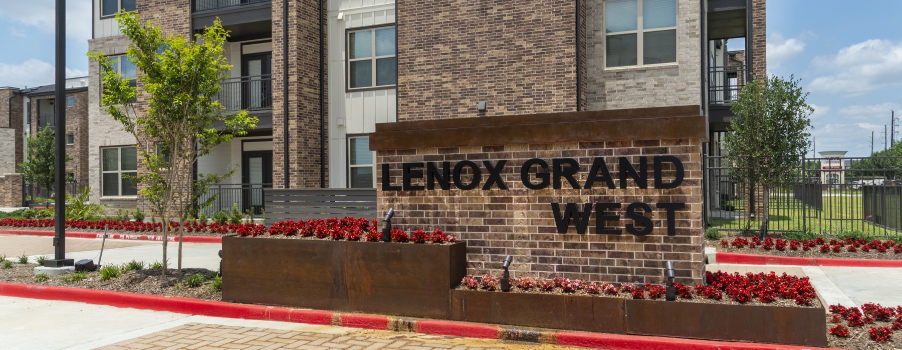 Lenox Grand West monument sign with red flowers